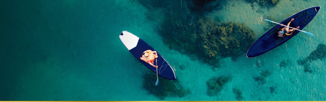 2 people on standup paddleboards with a reef below the water