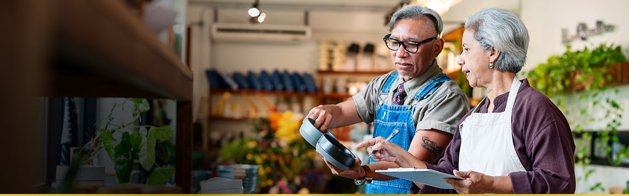 Two employees in a flower shop reviewing a tablet and discussing business operations.