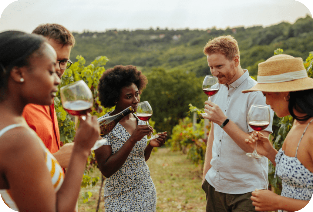 Group of people tasting red wine surrounded by grape vines